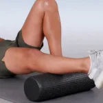 Textured yoga foam roller used for lower body recovery, supporting calf and leg muscle rolling on a training mat.