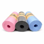 Three rolled TPE yoga mats in pink, grey, and blue, showing the side thickness and dual-layer design.