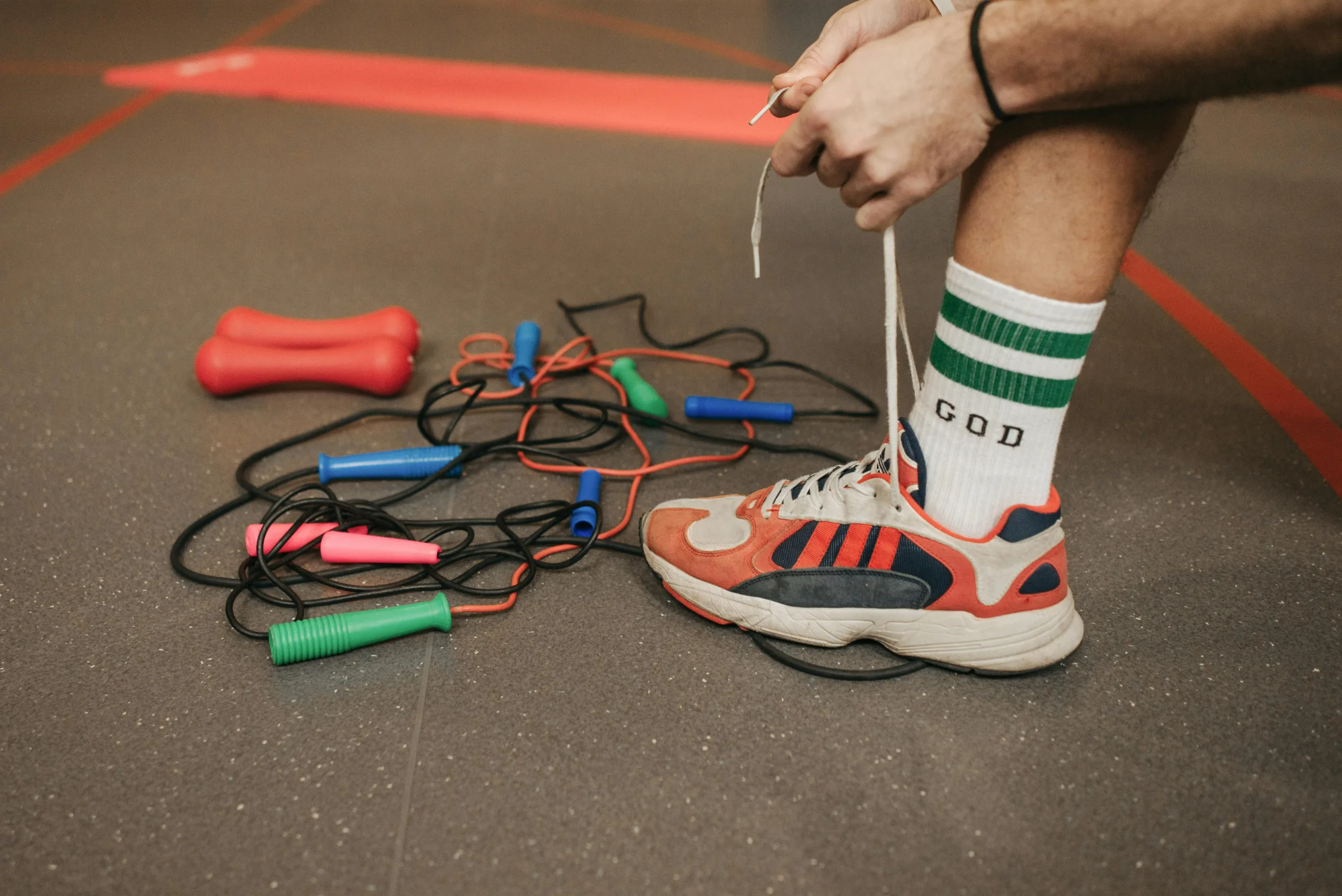 athlete sitting on gym floor with tangled plastic jump ropes choosing the right speed rope
